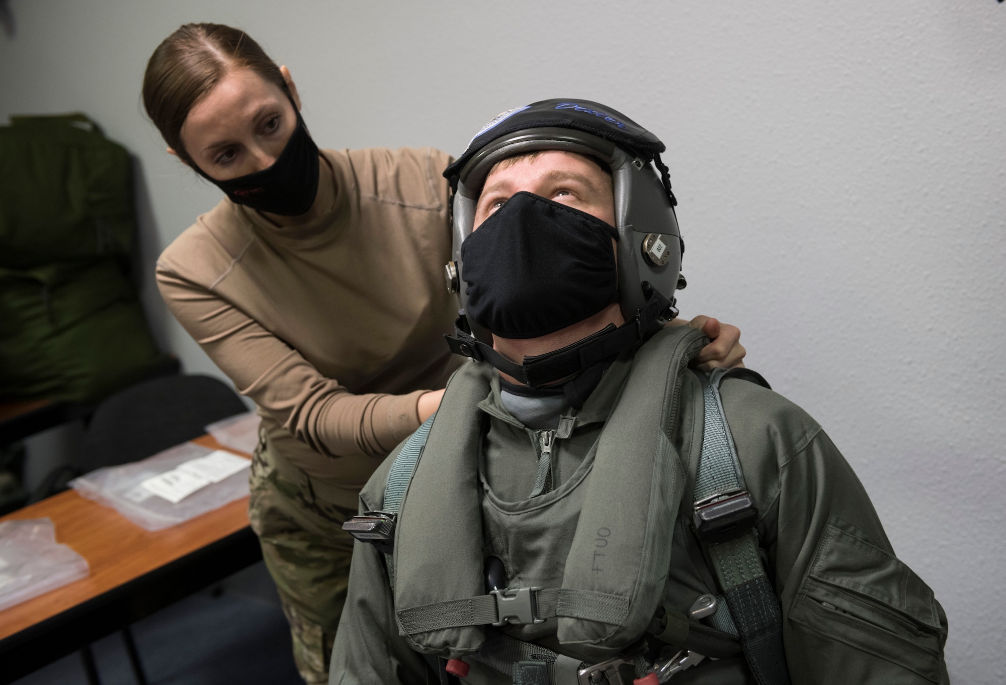 Airman 1st Class Lauren Wickman, left, an air flight equipment technician with the 3rd Operations Support Squadron checks F-22 Raptor pilot Capt. Jon “Dexter” Keranen’s range of motion while outfitting him in a newly received state-of-the-art integrated aircrew ensemble (IAE) flight suit and gear at Joint Base Elmendorf-Richardson, Alaska, Nov. 9, 2020. The brand-new, custom-fit gear mitigates adverse physiological effects on F-22 Raptor pilots by reducing the thermal burden while increasing mobility and comfort. (U.S. Air Force photo by Alejandro Peña)
