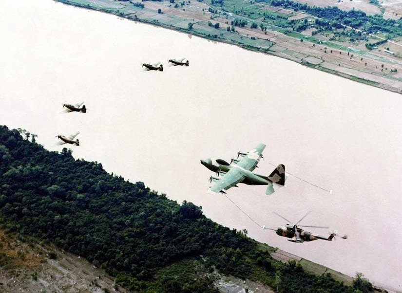 From a birds eye view, multiple aircraft fly along a body of water.