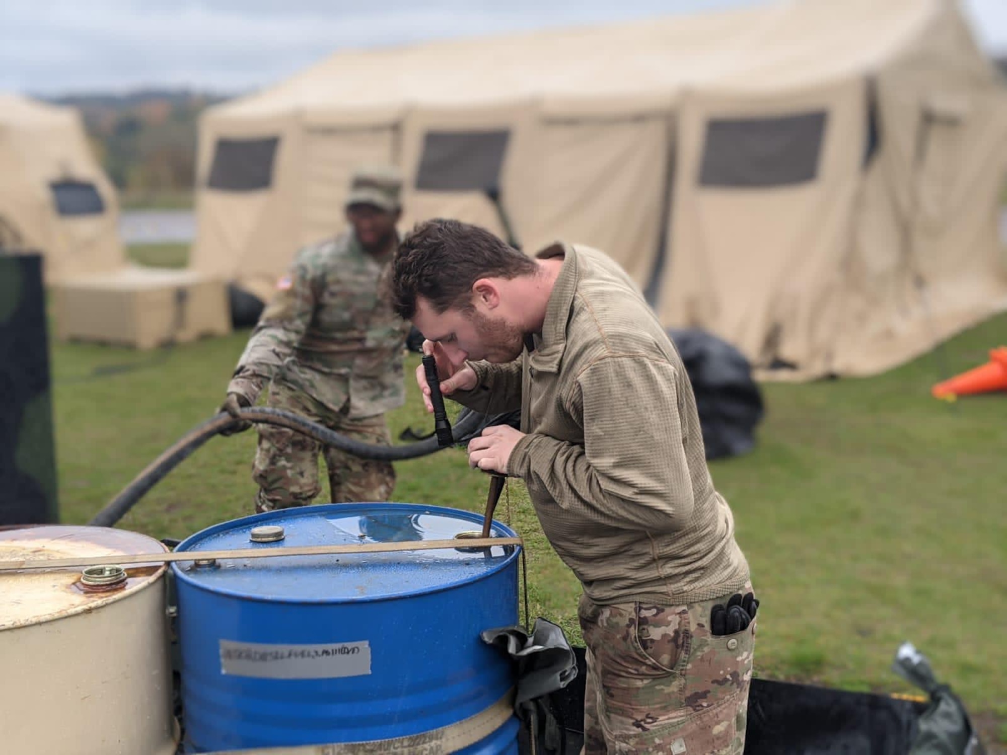 Photo of Airman checking fuel levels in a barrel