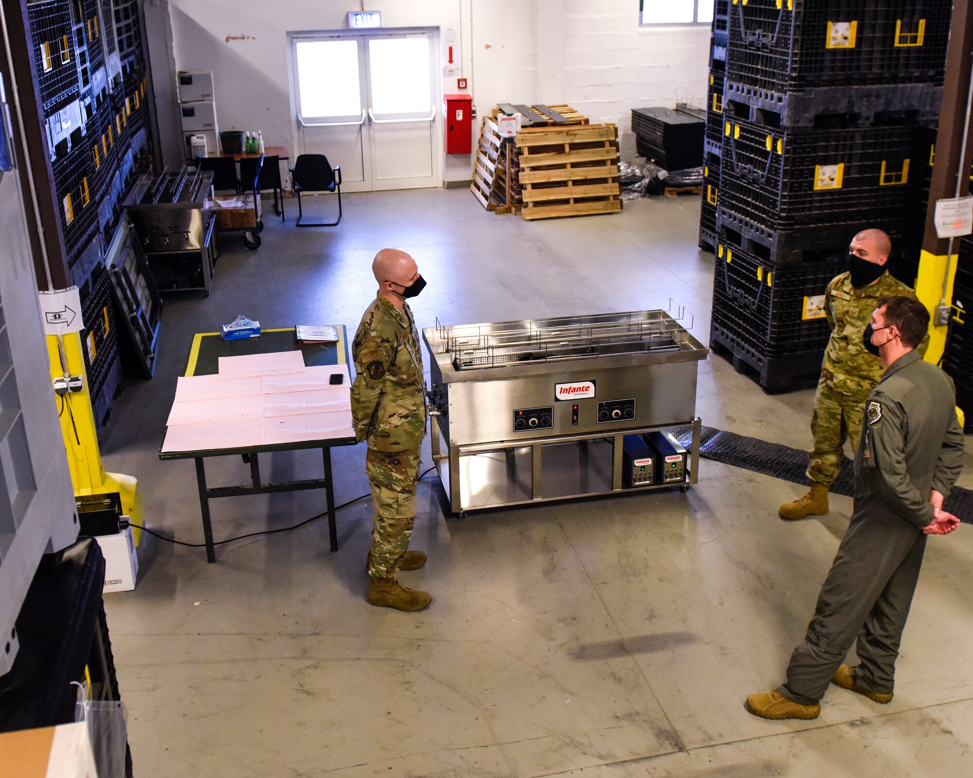 Two members of the 52nd Logistics Readiness Squadron greet U.S. Air Force Col. David C. Epperson, 52nd Fighter Wing commander, bottom right, before showing him a new ultrasonic weapons cleaner at Spangdahlem Air Base, Germany, Nov. 9, 2020. The machine allows for a two-member team to get 60 M4s inspection-ready on one typical workday shift. (U.S. Air Force photo by Senior Airman Chanceler Nardone)