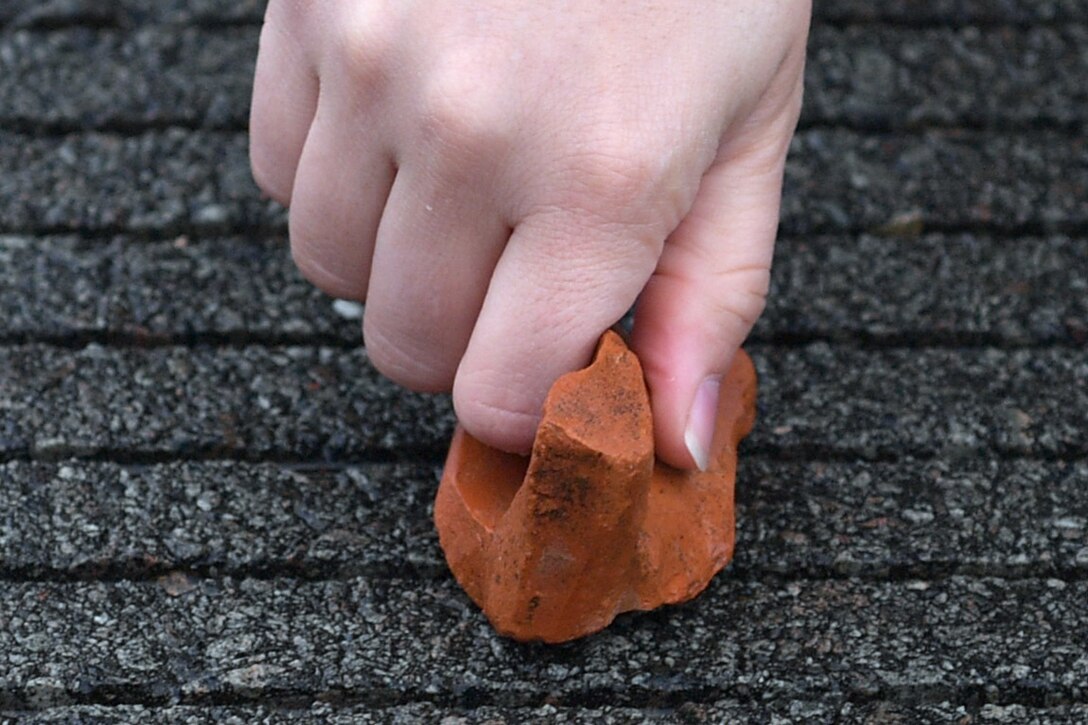 Close-up of a hand picking up a rock.