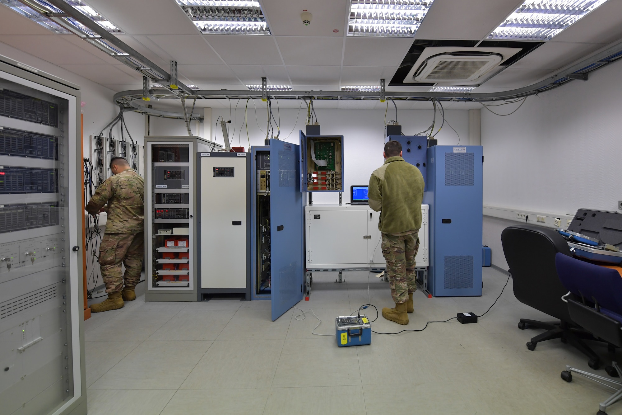 Two Airmen standing in a training room.