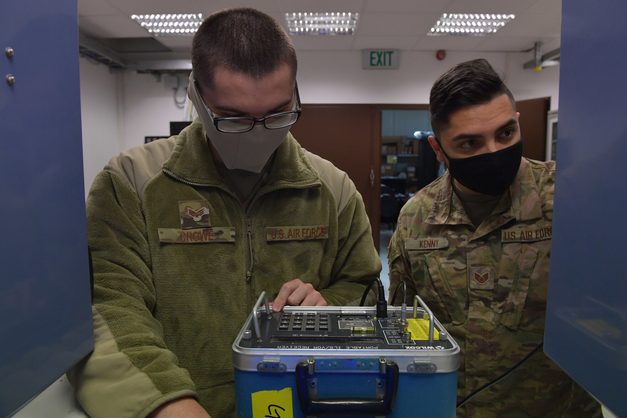 Two Airmen standing next to a portable instrument receiver.