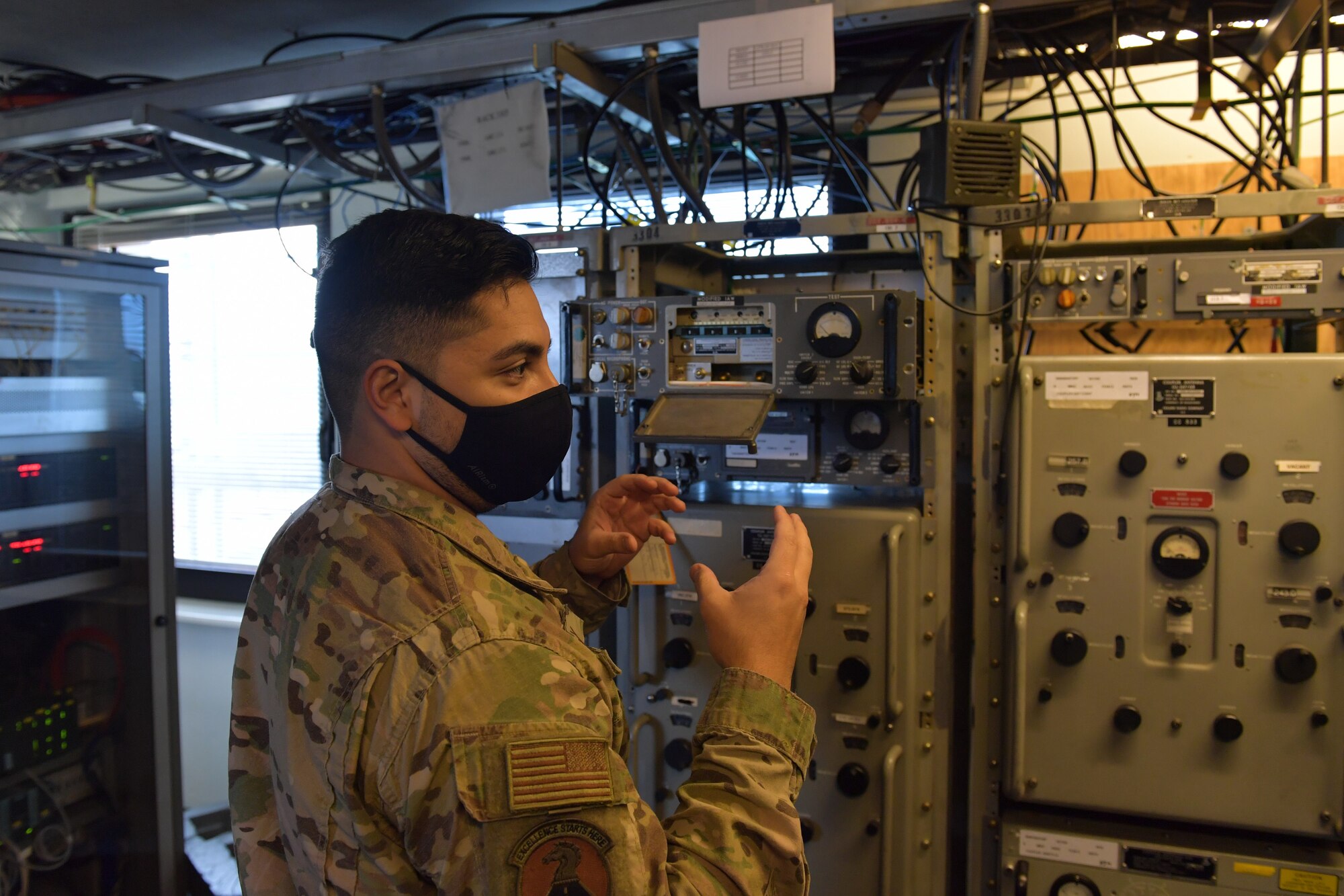 An Airman standing next to a radio.