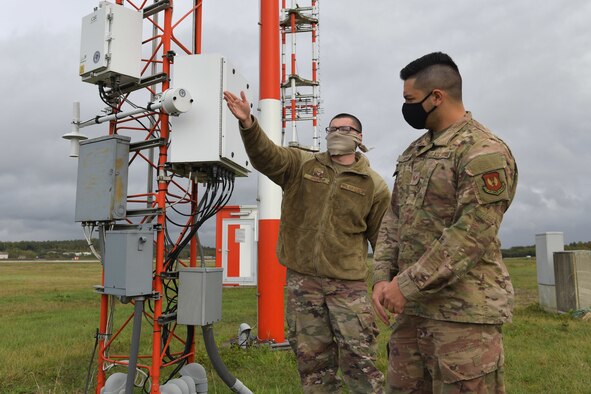 Two Airmen standing in a training room.