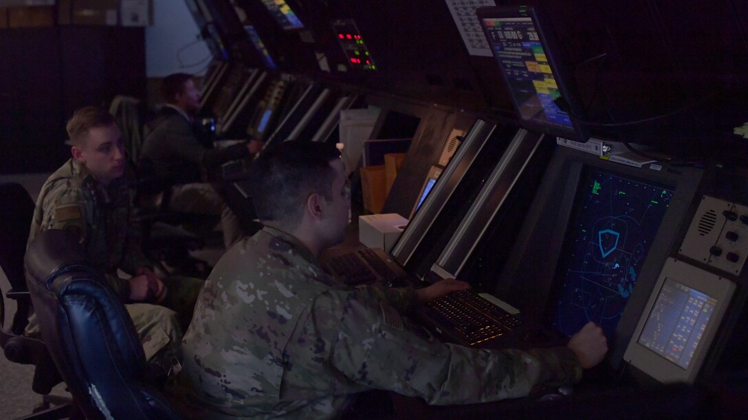 Airmen sitting at workstations with radar screens.