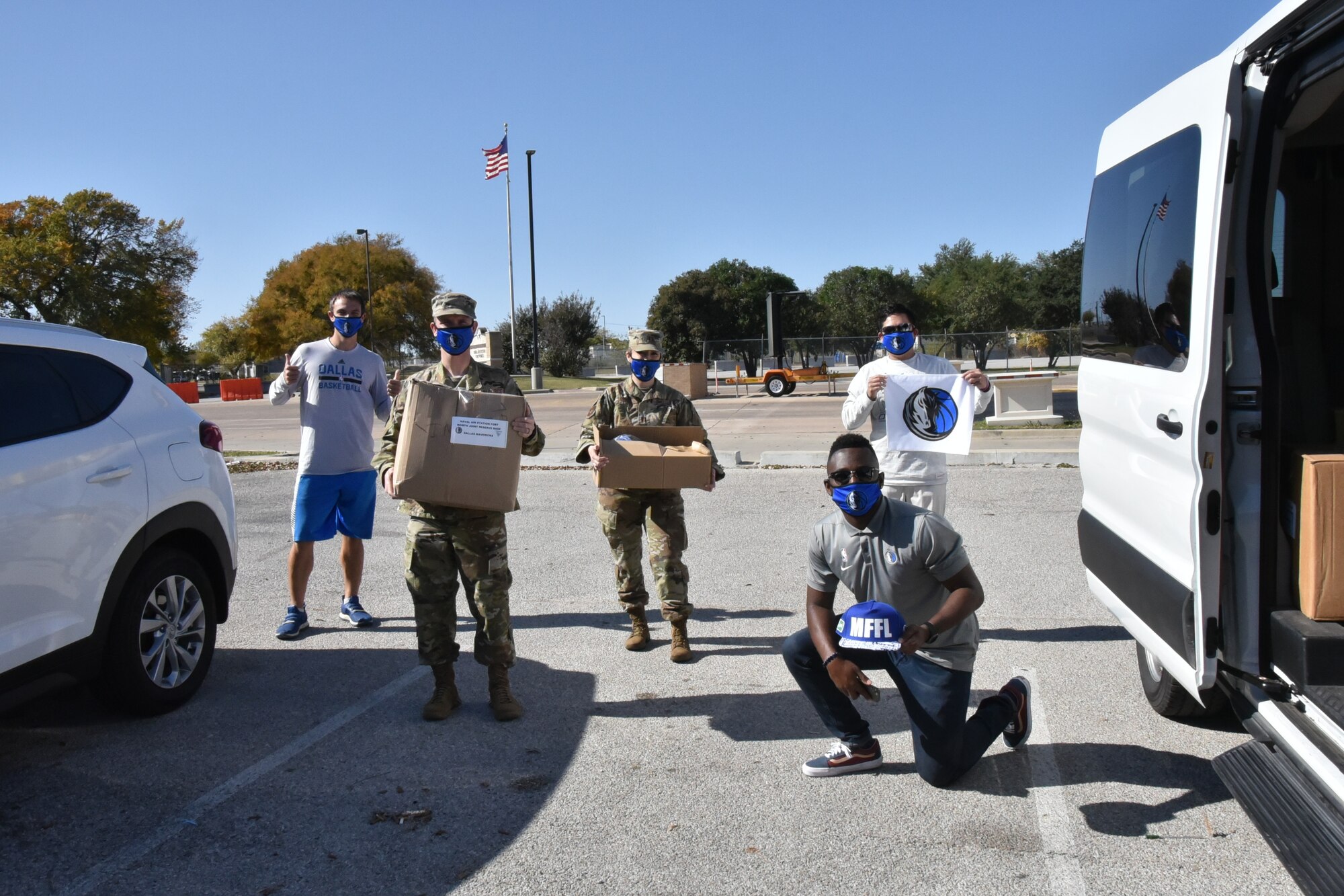 (Lower right) Cory Carter and fellow Dallas Mavericks community relations staff members distribute boxes of donated Mavs swag to 301st Fighter Wing Public Affairs members, Public Affairs Officer, Captain Jessica Gross and Senior Airman William Downs at U.S. Naval Air Station Joint Reserve Base Fort Worth, Texas on November 10, 2020. Due to COVID-19 health considerations, this year's event was held in lieu of the annual Hoops for Troops event. (U.S. Air Force photo by Master Sgt. Jeremy Roman)