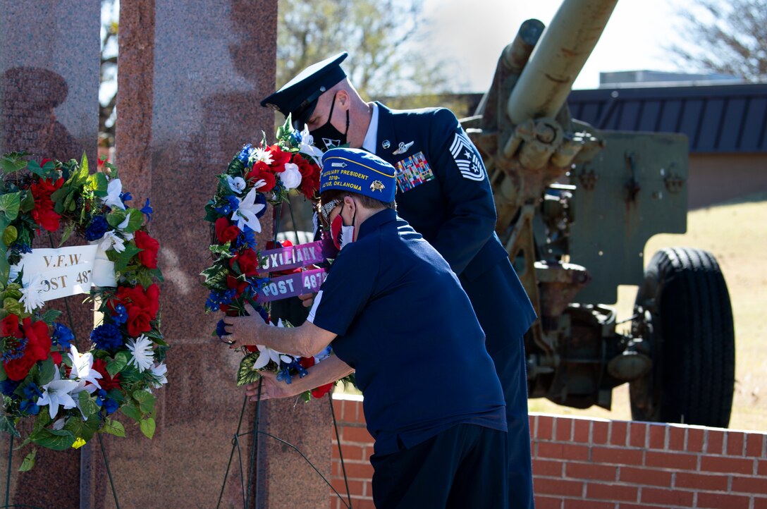 Veterans lay wreath at memorial.