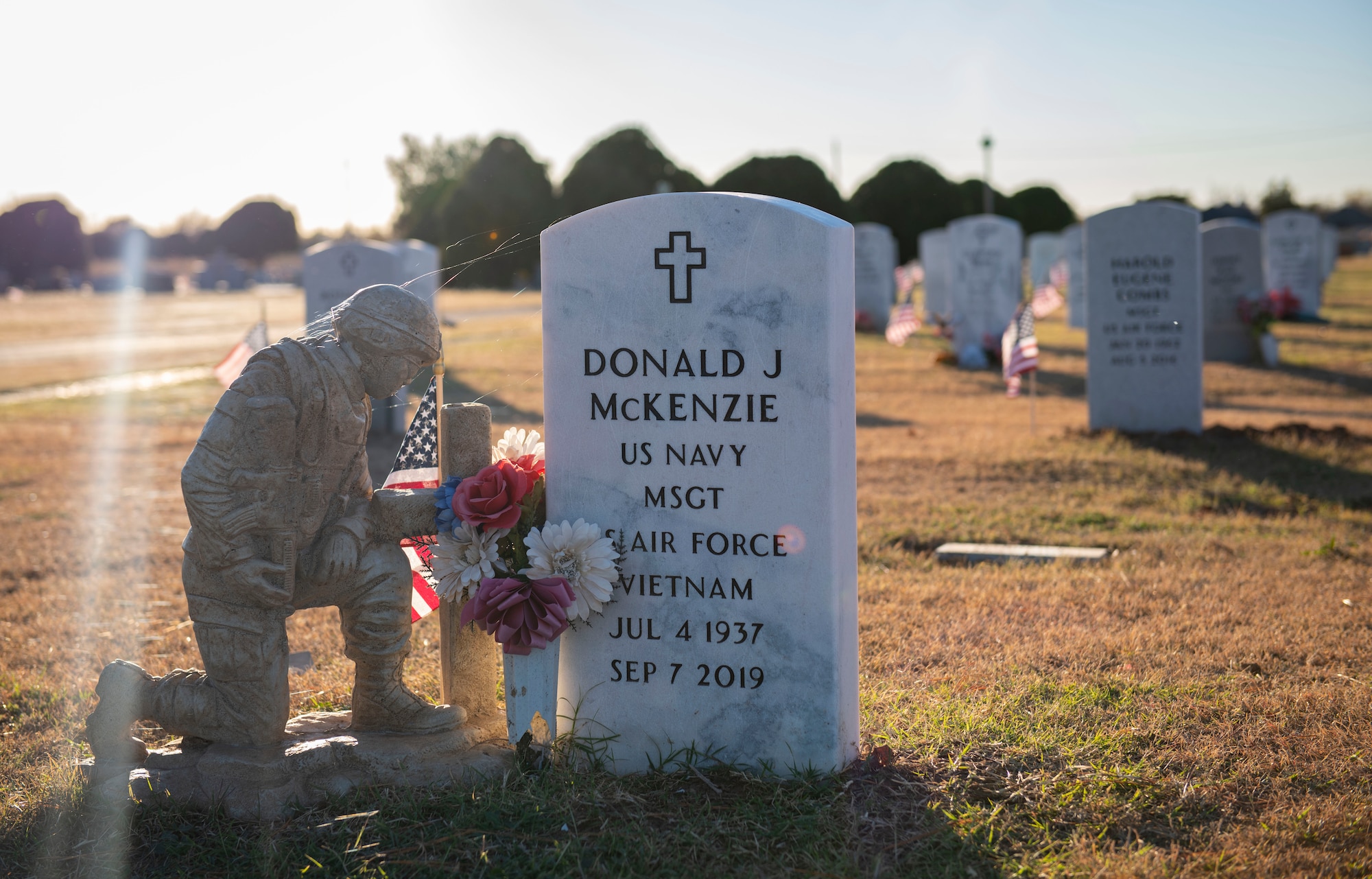 Person places a flag next to a veteran’s headstone.