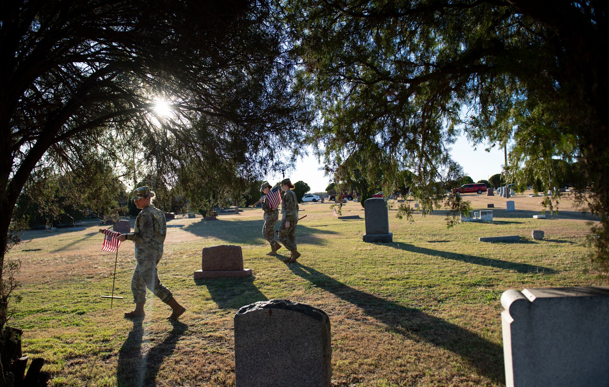 Person places a flag next to a veteran’s headstone.