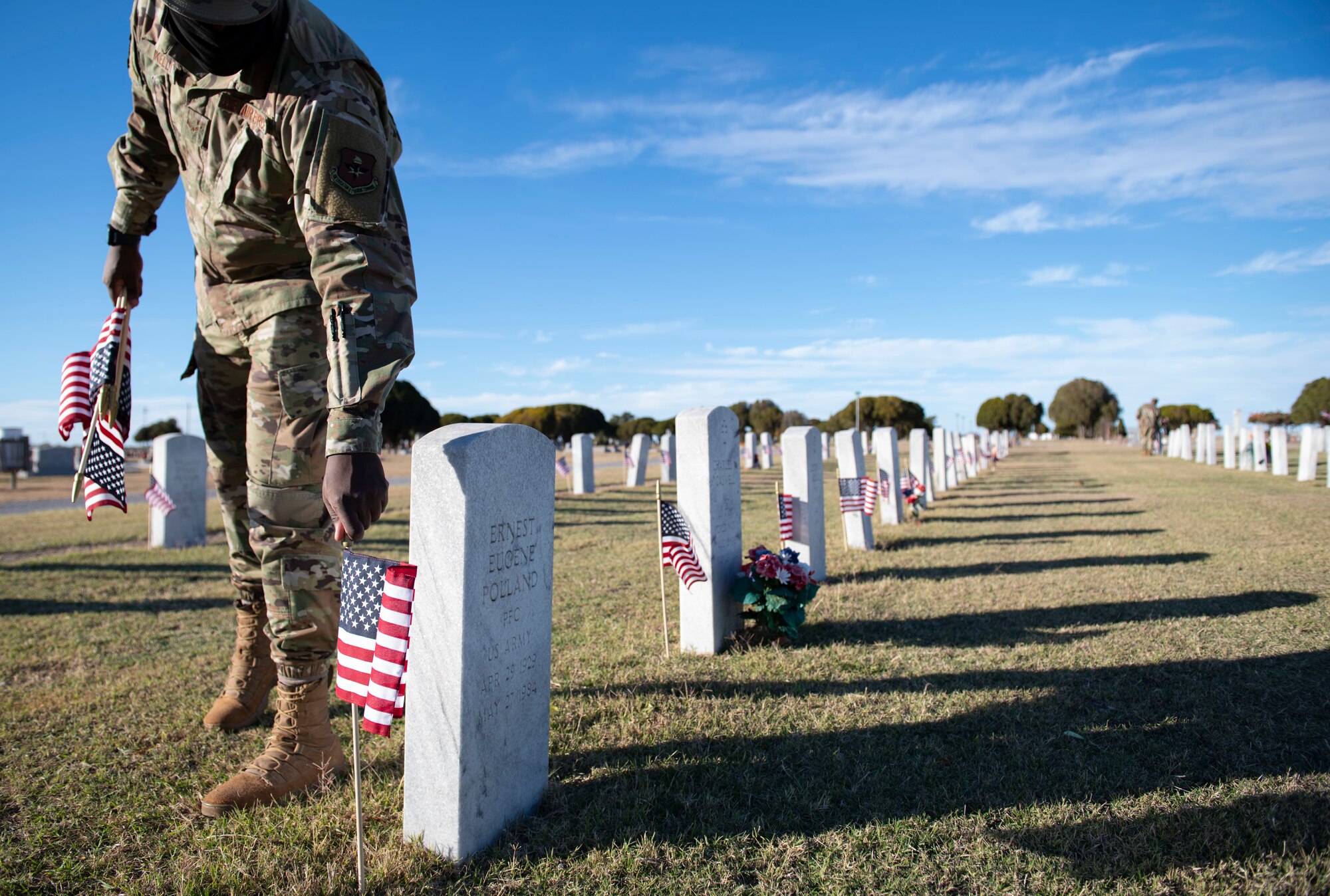 Person places a flag next to a veteran’s headstone.