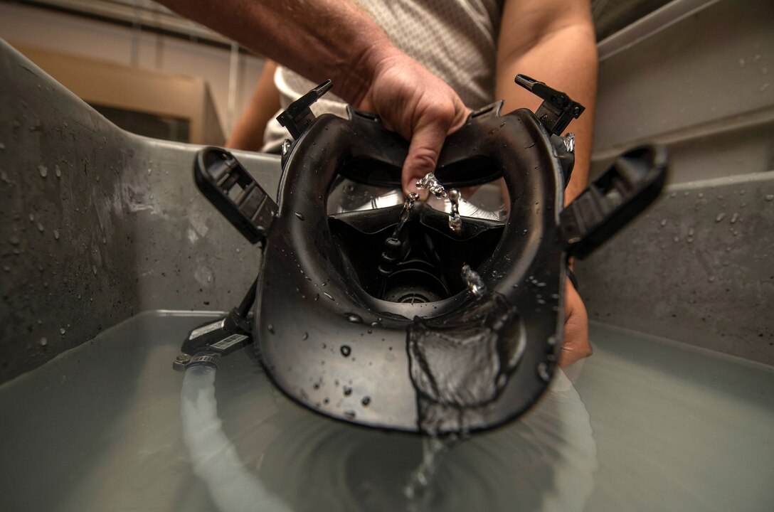 Personnel assigned to the 502nd Logistics Readiness Squadron  utilize a water pump to squeeze water through a gas mask drinking tube to clean out a gas mask more efficiently Nov. 13 at Joint Base San Antonio-Lackland.