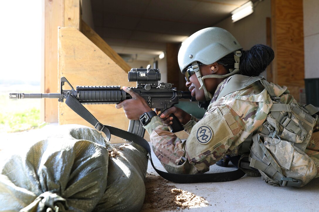 A soldier aims a weapon while lying on the ground.