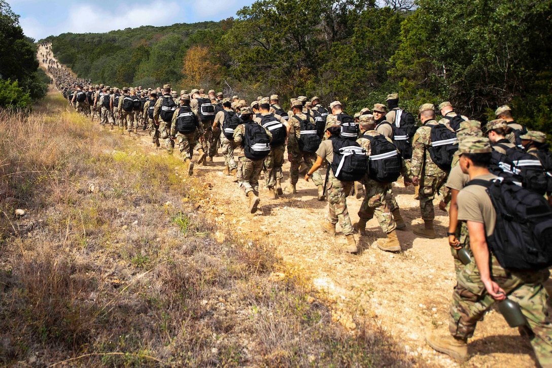 A large group of airmen march on a dirt road.