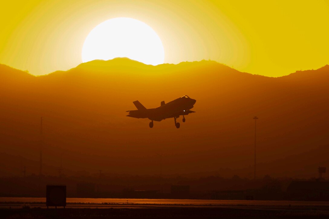 An aircraft flies as the sun rises in the background.