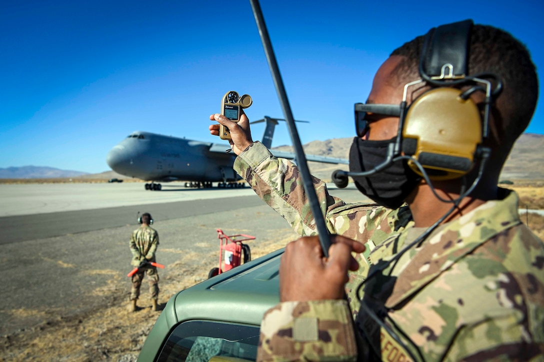 An airman holds a meter to measure wind speed, humidity and altitude.