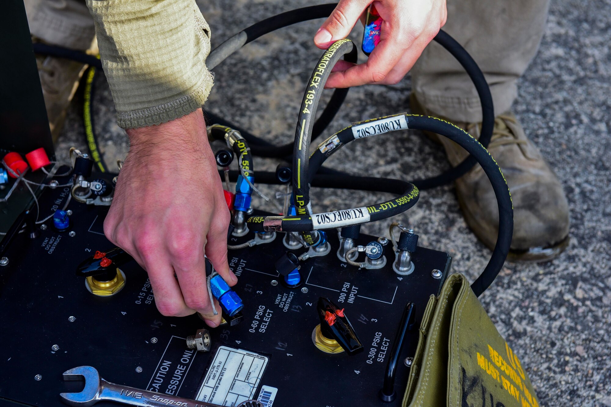 An Airman attaching a hose to a test box.