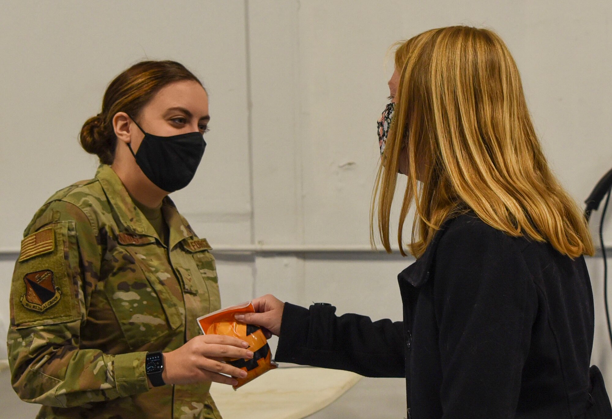 A spouse with the 88th Air Base Wing Senior Leader Spouse's hands candy to an Honor Guard Airman during their tour of the base on Wright-Patterson Air Force Base, Ohio, Oct. 30, 2020. This stop on their tour was not only for the spouse’s to familiarize themselves with the diverse people, workspaces and missions of WPAFB, but to thank the Honor Guard Airman for their service.