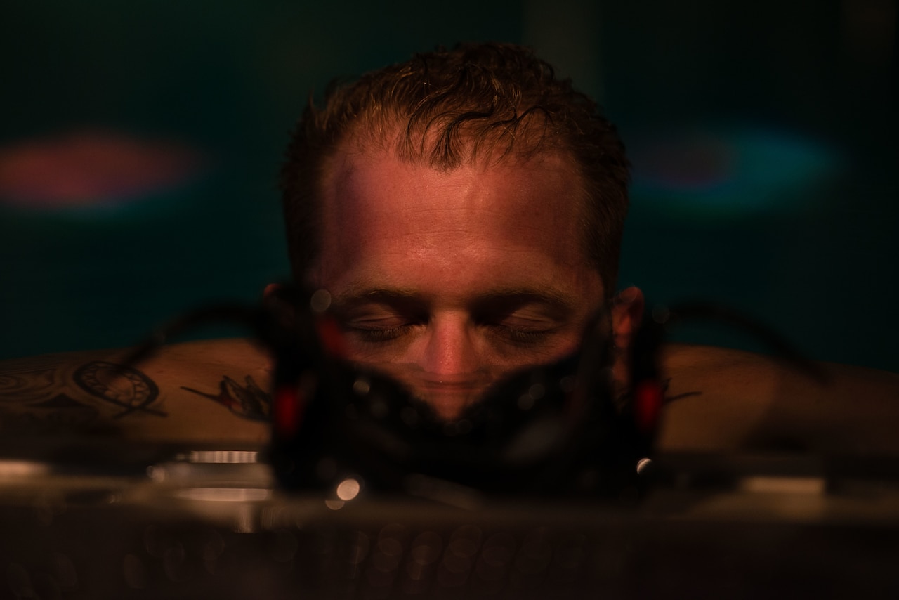 A man with his eyes shut is submerged in water above his nose.