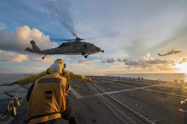 Sailors signal to MH-60S Sea Hawk helicopter attached to Golden Falcons of Helicopter Sea Combat Squadron 12 as it hovers over flight deck of USS McCampbell during visit, board, search, and seizure training exercise, South China Sea, July 22, 2016 (U.S. Navy/Elesia K. Patten)