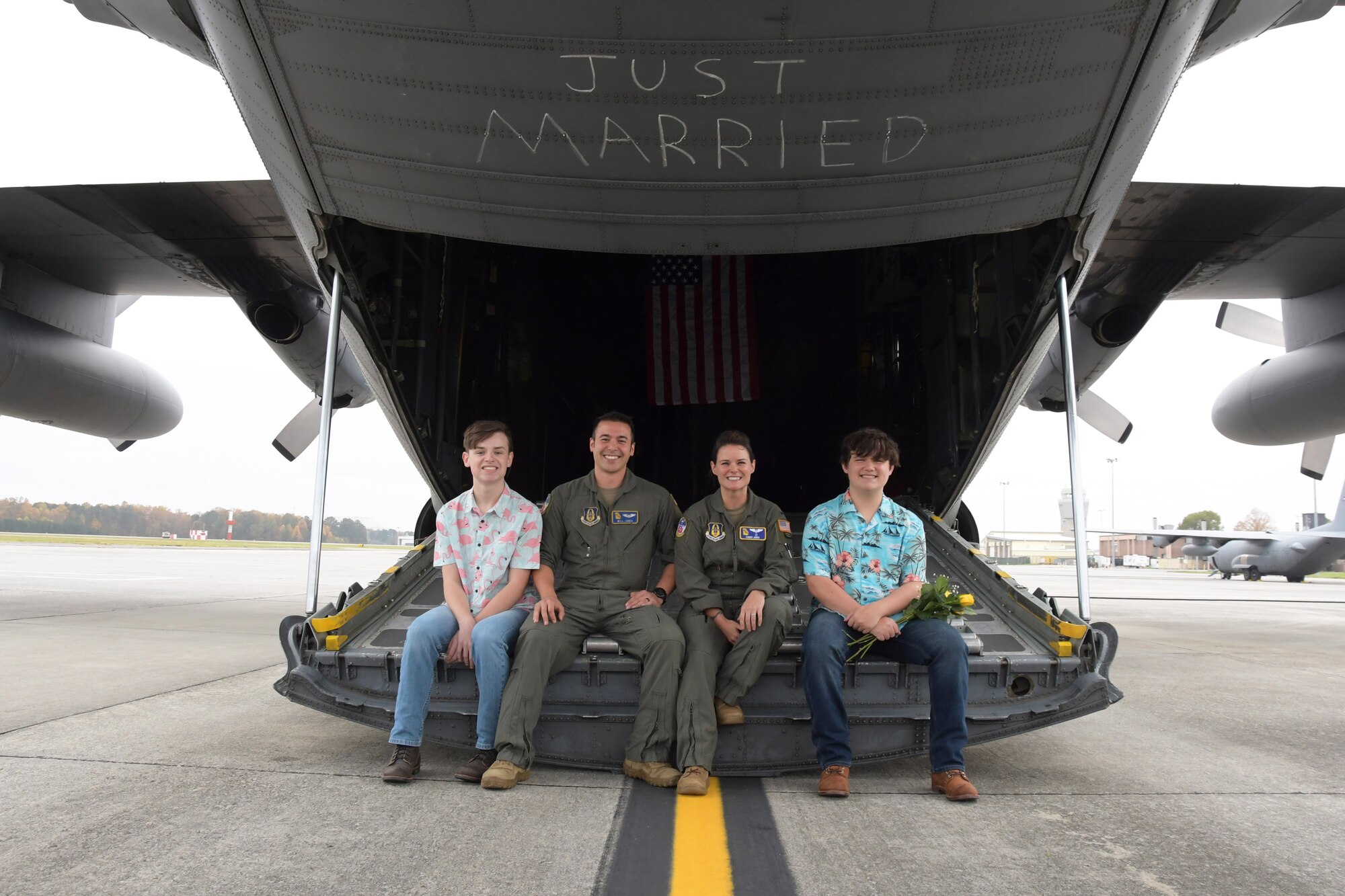 Capt. Will Jones, 700th Airlift Squadron pilot, and 1st Lt. Lyndsy Harrison, a 700th AS navigator, pose for a photo with Harrison's two sons shortly after a wedding ceremony held on the back of a C-130H3 Hercules at Dobbins Air Reserve Base, Ga. on Nov. 10, 2020. The couple came up with the idea to get married on the back of a C-130 to honor their love of aviation. (U.S. Air Force photo/Andrew Park)
