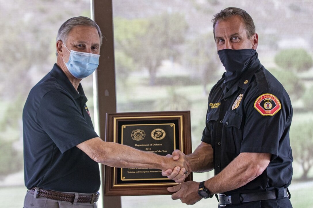 Acting Under Secretary of the Navy Gregory J. Slavonic hands a plaque for the Department of Defense’s Large Fire Department of the Year award to Ken Helgerson, the fire chief for the Camp Pendleton Fire Department, during a ceremony at Marine Memorial Golf Course on Marine Corps Base Camp Pendleton, California, Oct. 27, 2020. This is the sixth time CPFD has been selected for the award. Slavonic traveled to Southern California to meet with sailors and Marines, gaining enhanced insight to fleet modernization, cyber and readiness efforts that will ultimately build a more lethal force. (U.S. Marine Corps photo by Lance Cpl. Drake Nickels)