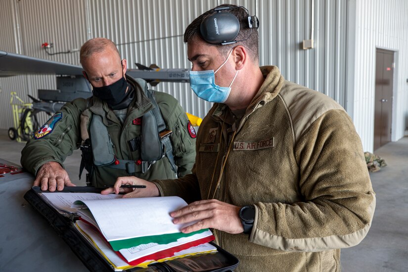 Two airmen look at paperwork.