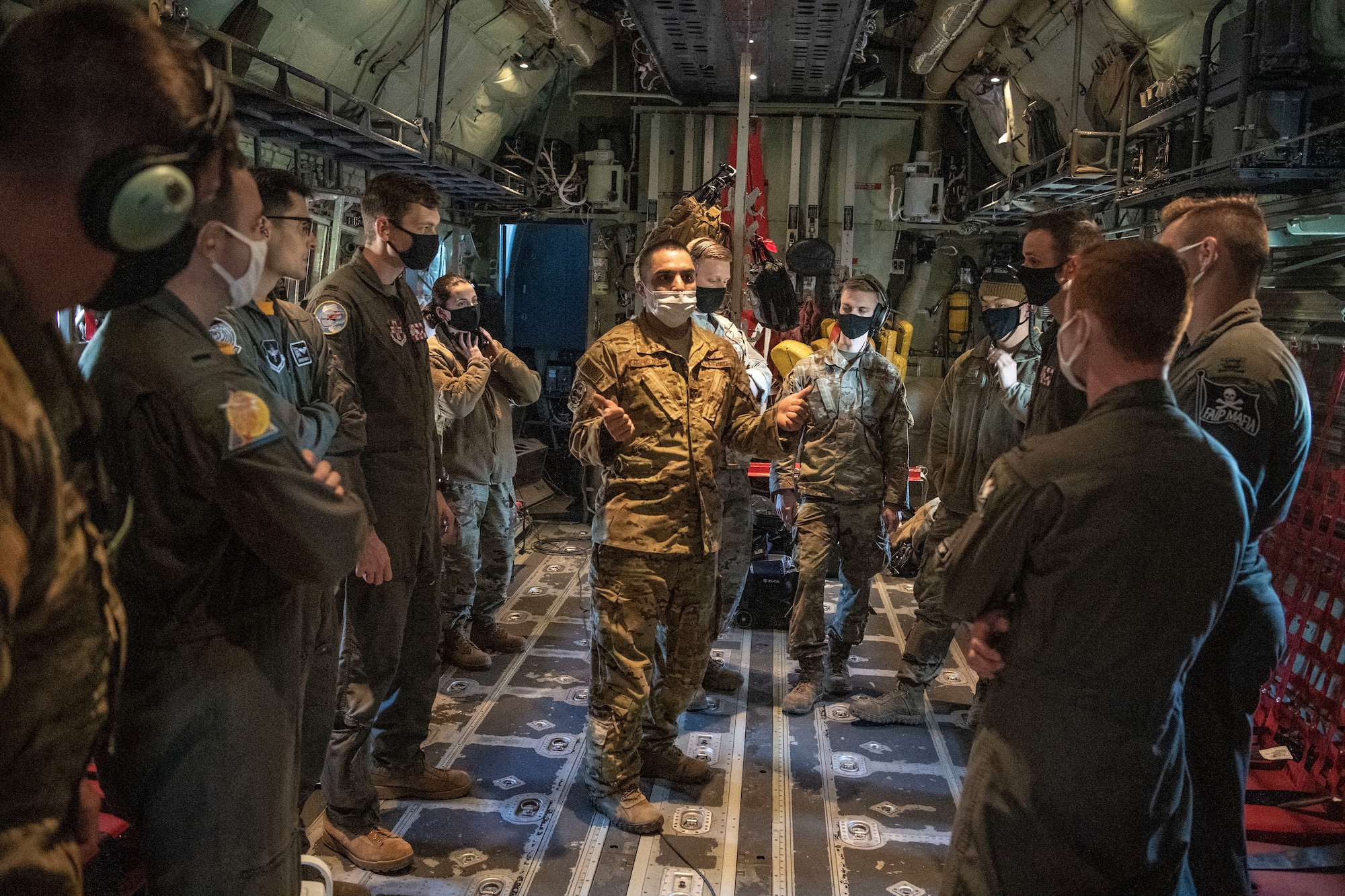 A loadmaster speaks with student pilots before a flight.