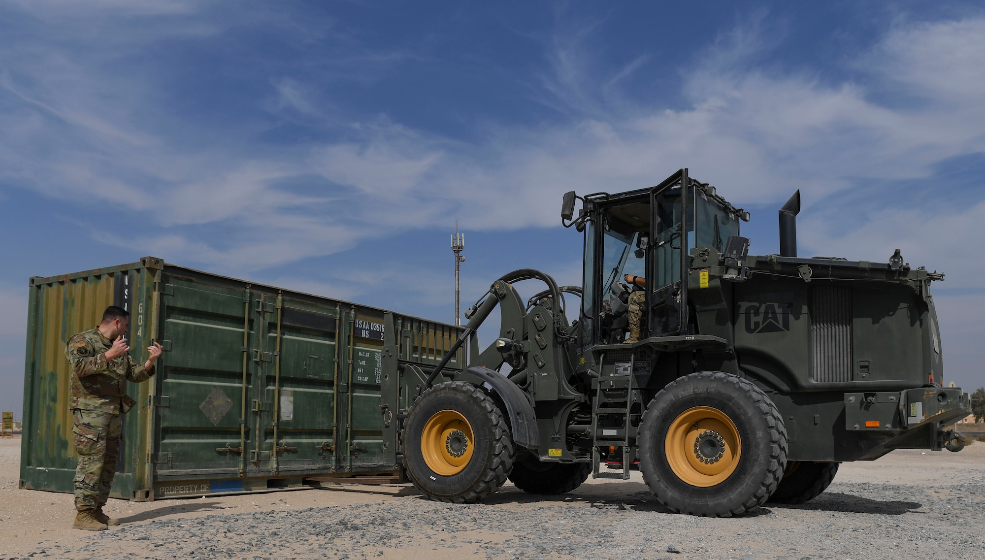 U.S. Air Force Tech. Sgt. Christopher Pierce, 407th Expeditionary Support Squadron logistics readiness flight ground transportation supervisor, guides Airman 1st Class Gabriel Flores, 407th ESPTS LRF ground transportation operator, toward a container at Ahmed Al Jaber Air Base, Kuwait, Nov. 6, 2020.