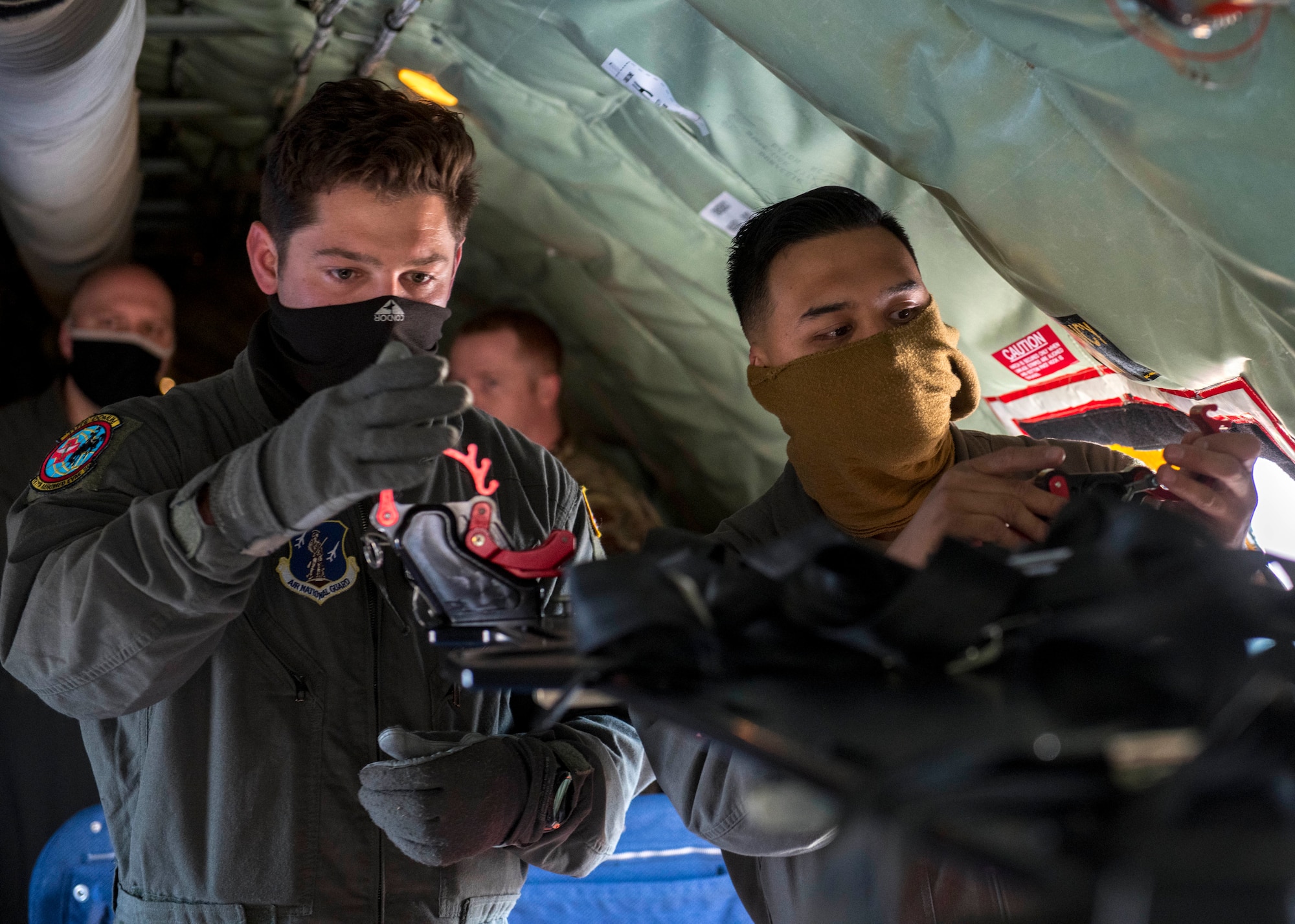 Wyoming Air National Guard Airman 1st Class Ashton Davila (left), 187th Aeromedical Evacuation Squadron medical technician, and U.S. Air Force Senior Airman Jeremiah Guinto (right), 92nd Air Refueling Squadron boom operator, configure a stanchion on a KC-135 Stratotanker prior to an aeromedical evacuation mission at Travis Air Force Base, California, Nov. 7, 2020. Fairchild Airmen worked alongside Wyoming Air National Guard Airmen from the 187th AES and 18th AES, traveling across the Pacific Ocean to Kadena Air Base in Japan. (U.S. Air Force photo by Senior Airman Lawrence Sena)