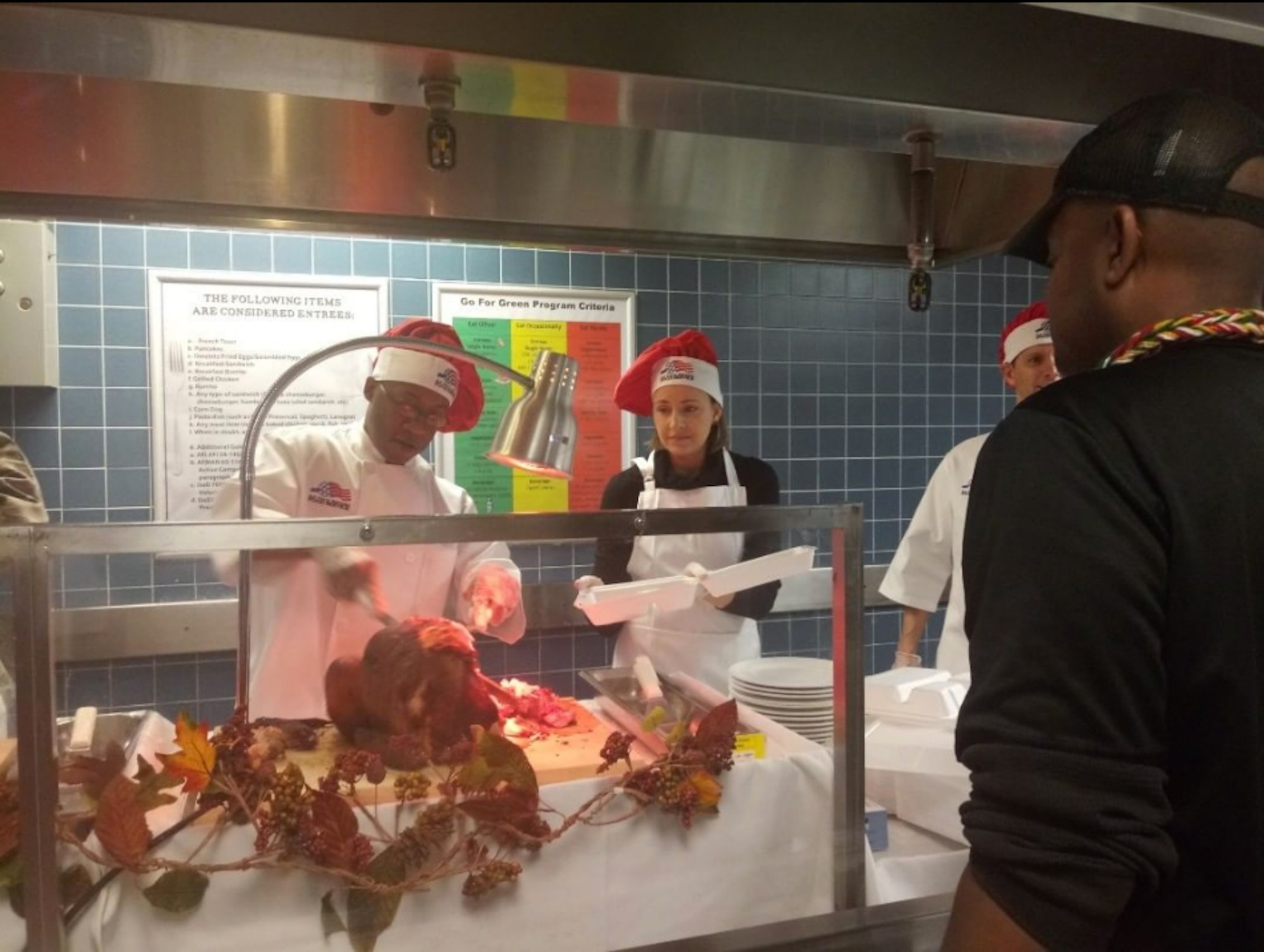 Wing commander Colonel Marks  dressed in chefs uniform and chefs hat while carving a turkey for Airmen to eat on Thanksgiving Day.