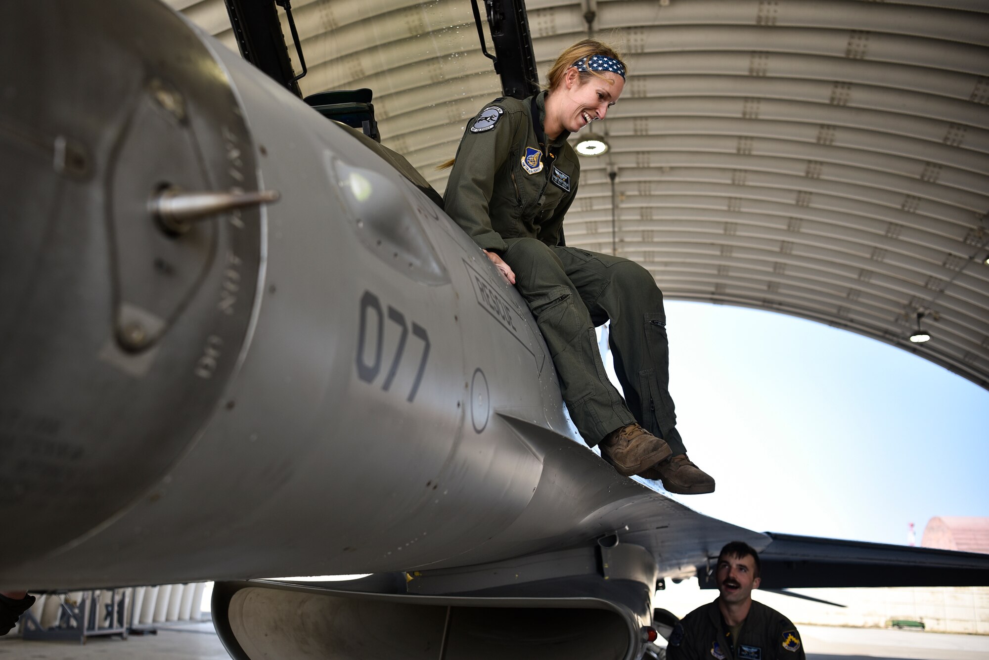 A pilot hops out of an F-16.