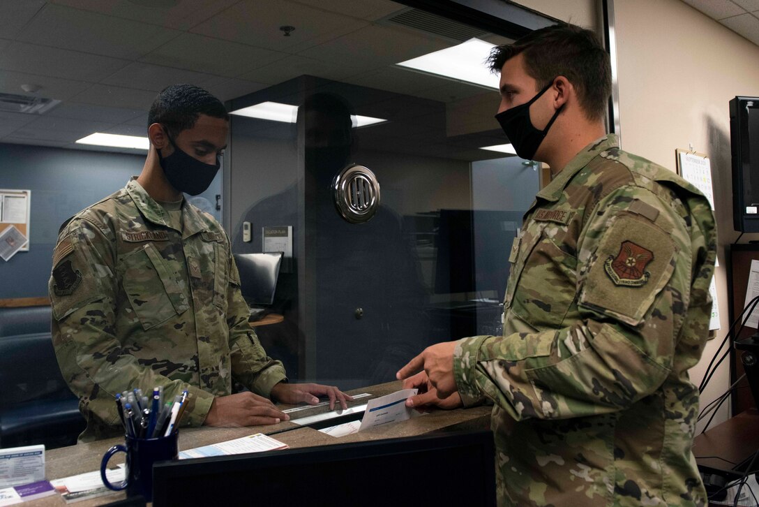 Airman hands paperwork to other Airman