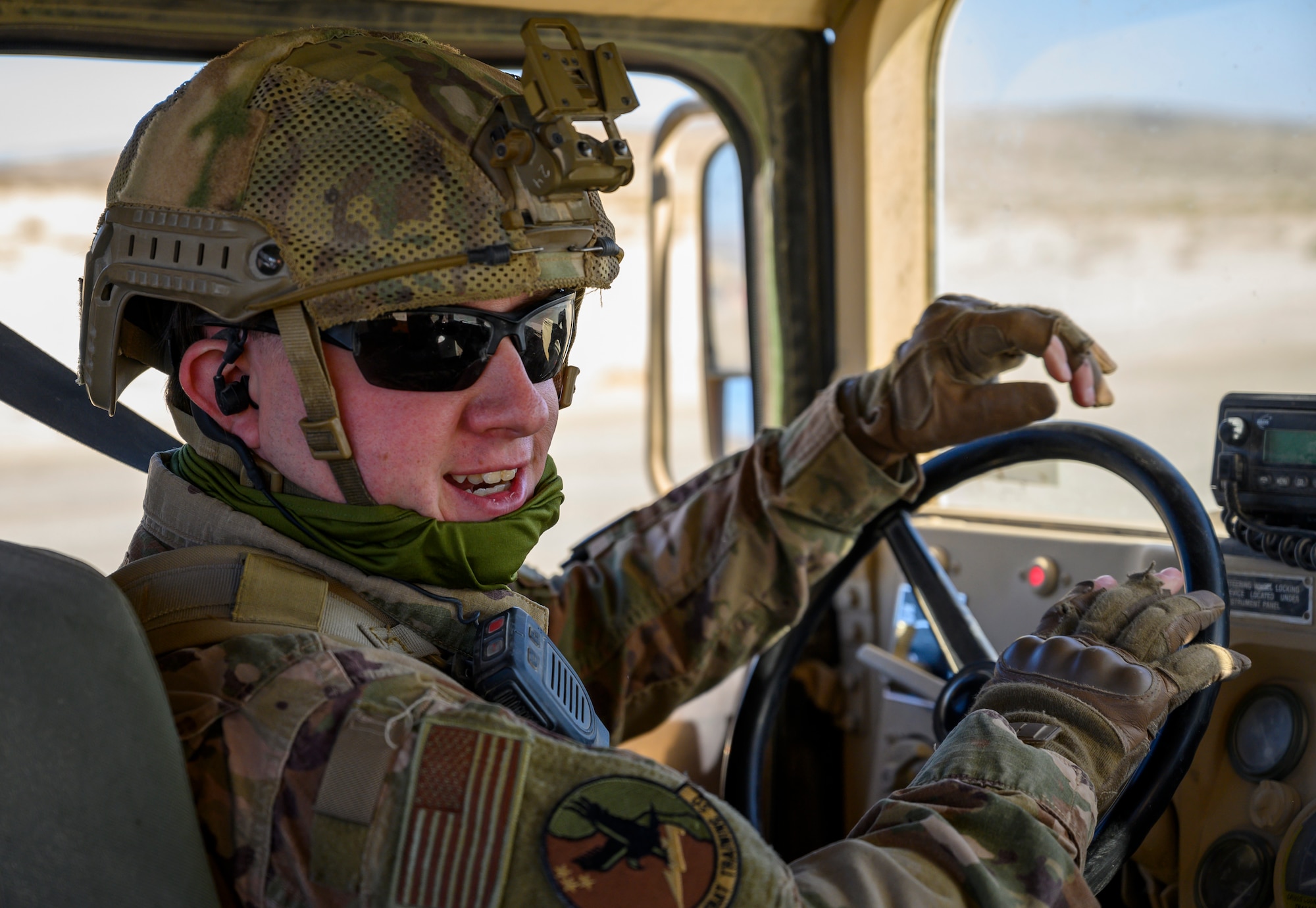 Airman smiles while seated behind the steering wheel of a Humvee.