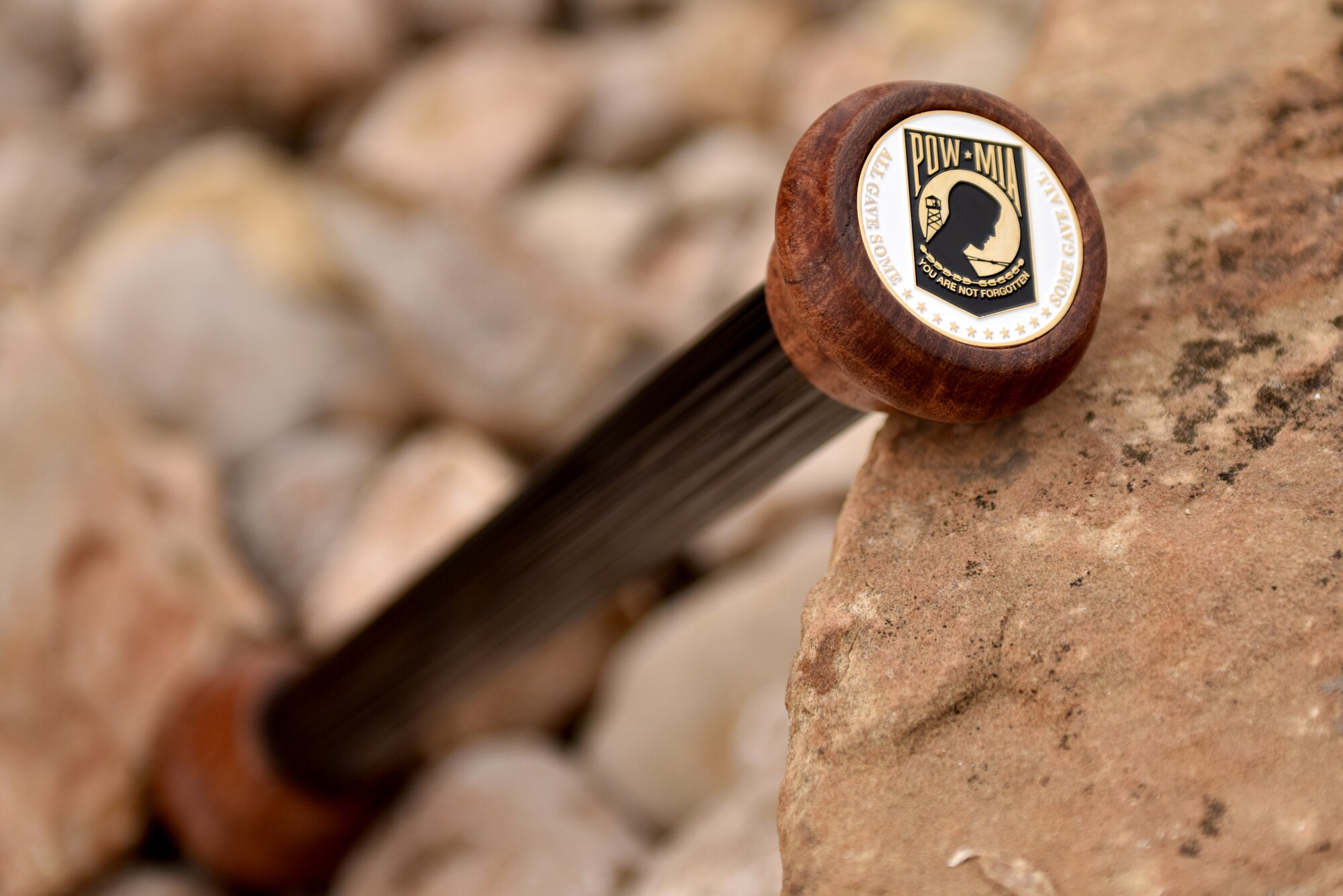 The Prisoner of War and Missing in Action baton is displayed on a rock before the beginning of the race at Mathis Fitness Center track on Goodfellow Air Force Base, Texas, Nov. 13, 2020. The baton was made from a fire ladder rung and held a POW-MIA coin in each end. (U.S. Air Force Photo by Staff Sgt. Seraiah Wolf)