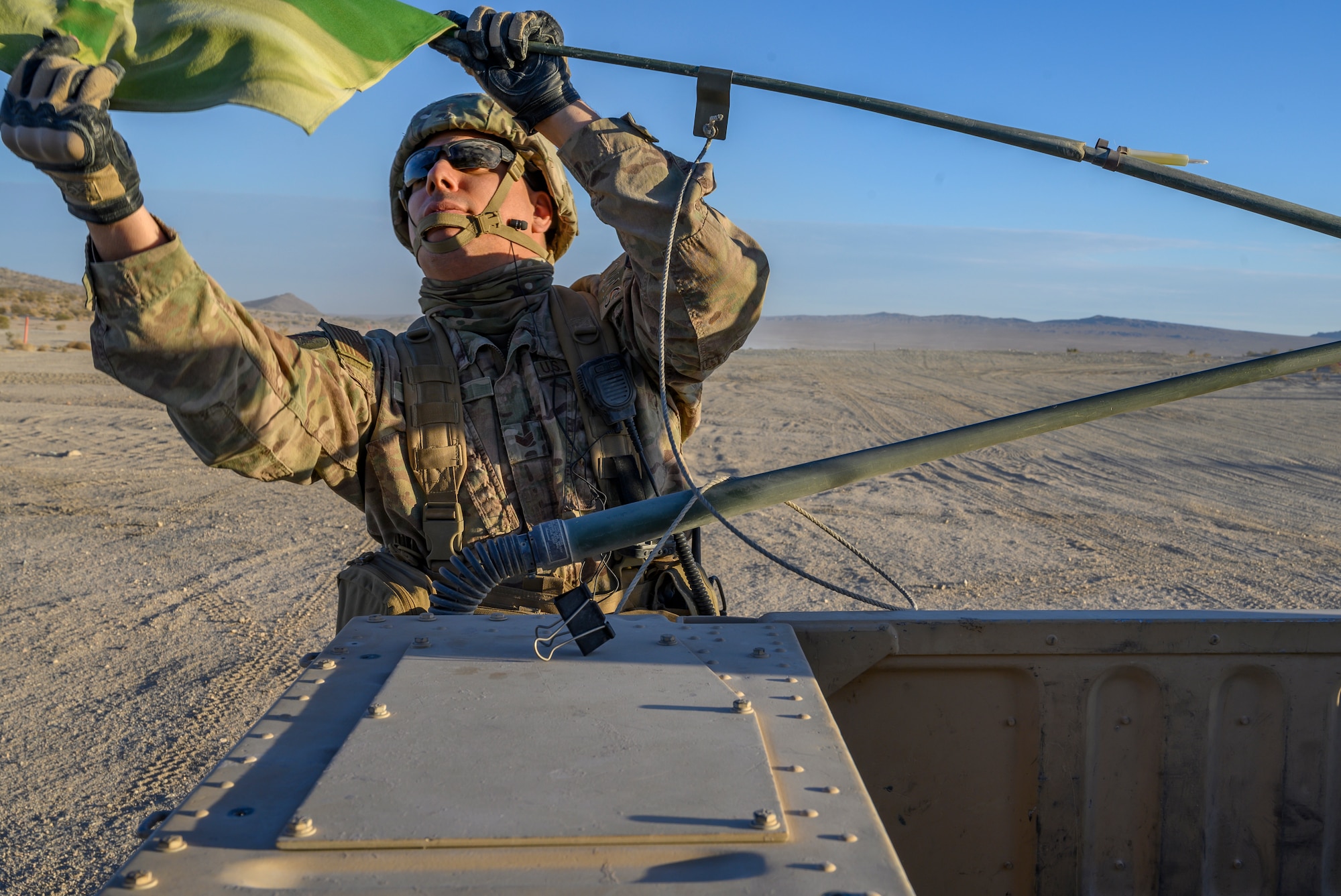 Airman grabs a flag on the back of a Humvee.