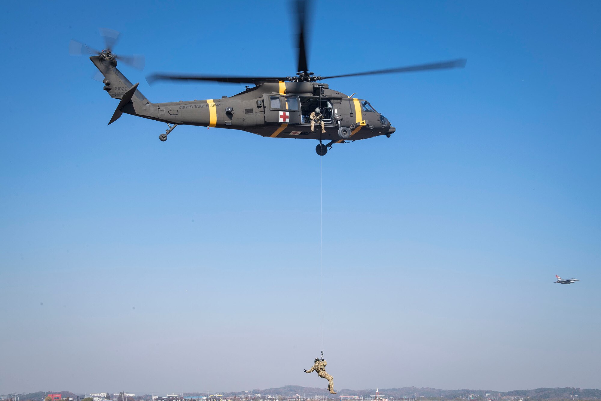 An HH-60m aircrew member from U.S. Army Garrison Humphreys 3-2 General Support Aviation Battalion lifts an Osan Air Base pilot during hoist training at Osan AB, Republic of Korea, Nov. 12, 2020. Osan’s 51st Fighter Wing Survival, Evasion, Resistance and Escape trainers and the 3-2 GSAB partnered to test individual’s high-risk survival readiness. (U.S. Air Force photo by Senior Airman Greg Nash)