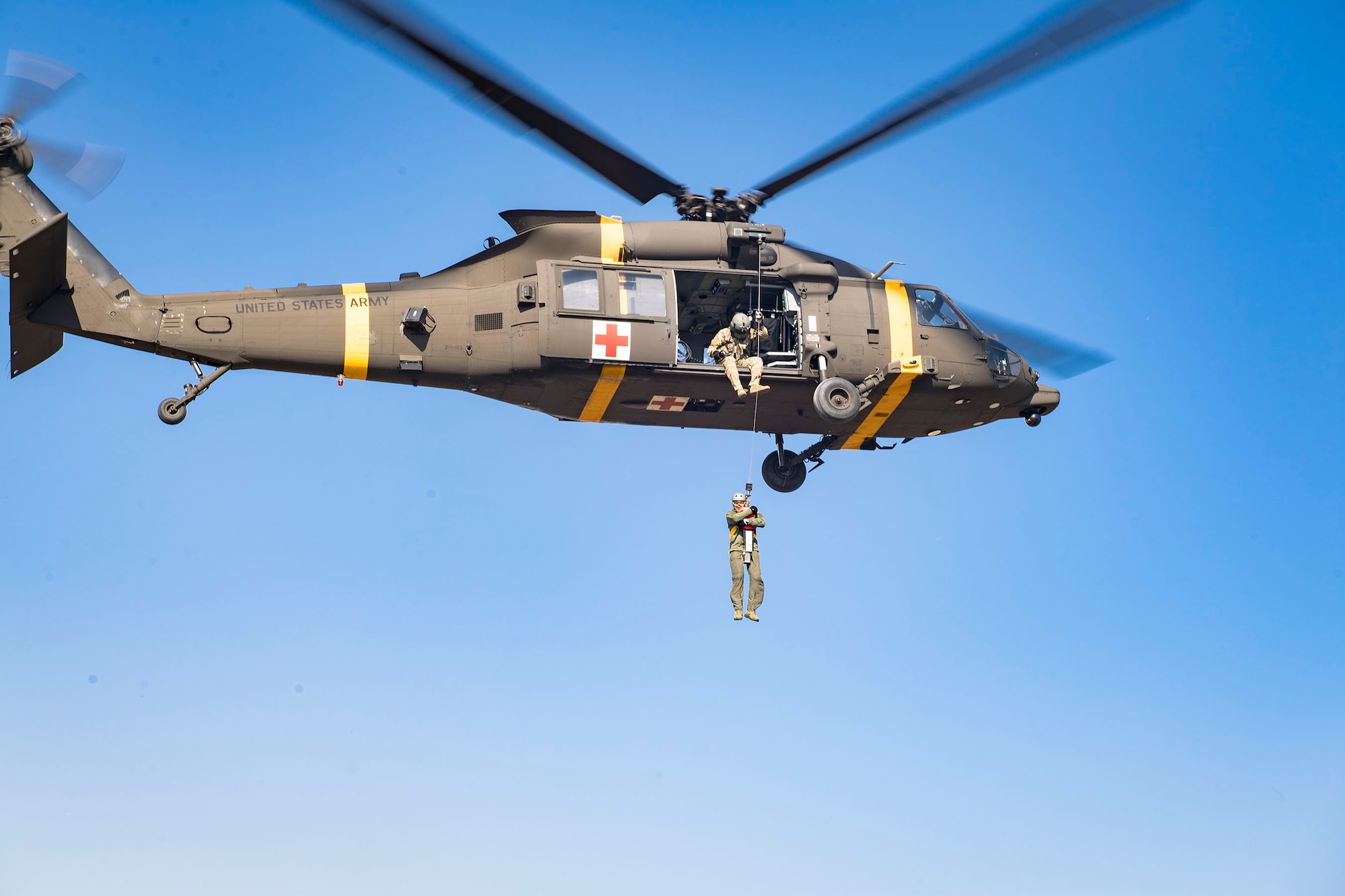 An HH-60m aircrew member from U.S. Army Garrison Humphreys 3-2 General Support Aviation Battalion lifts an Osan Air Base pilot during hoist training at Osan AB, Republic of Korea, Nov. 12, 2020. Osan’s 51st Fighter Wing Survival, Evasion, Resistance and Escape trainers and the 3-2 GSAB partnered to test individual’s high-risk survival readiness. (U.S. Air Force photo by Senior Airman Greg Nash)