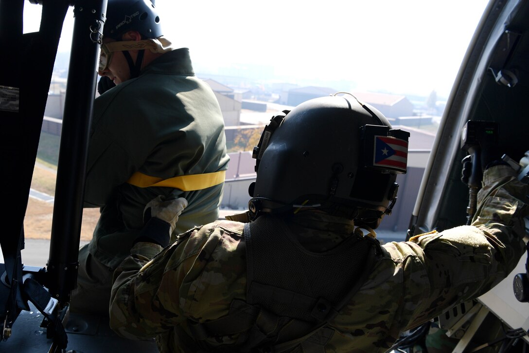 An HH-60m aircrew member from U.S. Army Garrison Humphreys 3-2 General Support Aviation Battalion secures an Osan Air Base pilot during hoist training, at Osan AB, Republic of Korea, Nov. 12, 2020. Osan’s 51st Fighter Wing Survival, Evasion, Resistance and Escape trainers and the 3-2 GSAB partnered to test individual’s high-risk survival readiness. (U.S. Air Force photo by Senior Airman Noah Sudolcan)