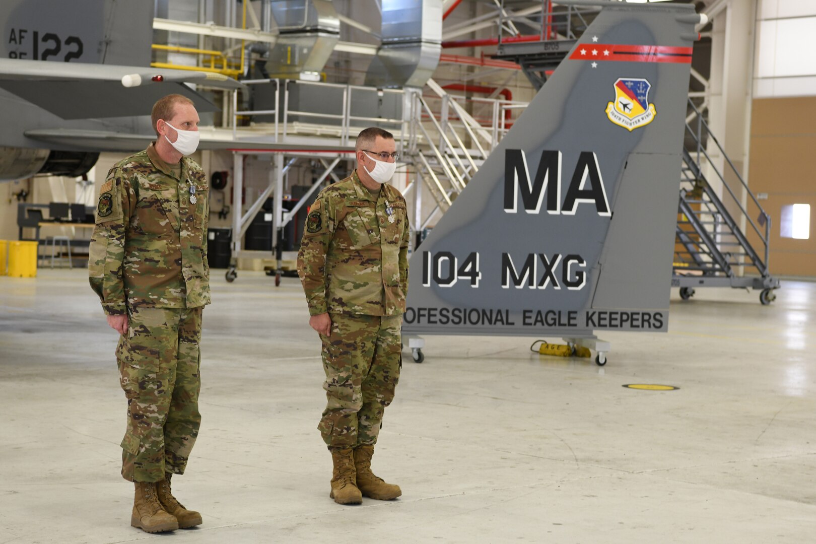 Master Sgt. Leo Burbee, 104th Maintenance Group structural maintenance supervisor, and Master Sgt. Bob Oleksak, 104MXG fabrication element supervisor, stand at attention after receiving the Air Force Achievement Medal during a ceremony Nov. 14, 2020, at Barnes Air National Guard Base, Massachusetts.