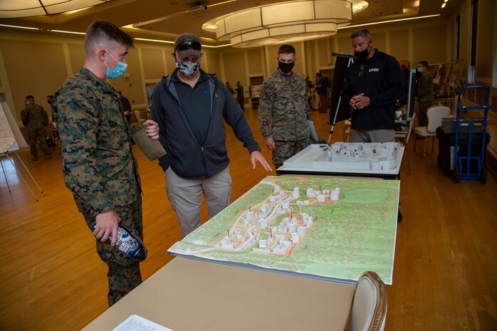 David W. VanHorn, center, the assistant site lead at the Infantry Immersion Trainer, Marine Corps Base Camp Lejeune, shows a Marine with 2nd Marine Division a new range under construction that simulates real life scenarios that can take place during combat missions during the Warfighter Training Symposium at Marston Pavilion on MCB Camp Lejeune, North Carolina, Nov. 4, 2020. The symposium provided more than 150 leaders with information on facilities available on MCB Camp Lejeune to Marines for training and provides an opportunity to inquire about range complex capabilities. (U.S. Marine Corps photo by Cpl. Ginnie Lee)