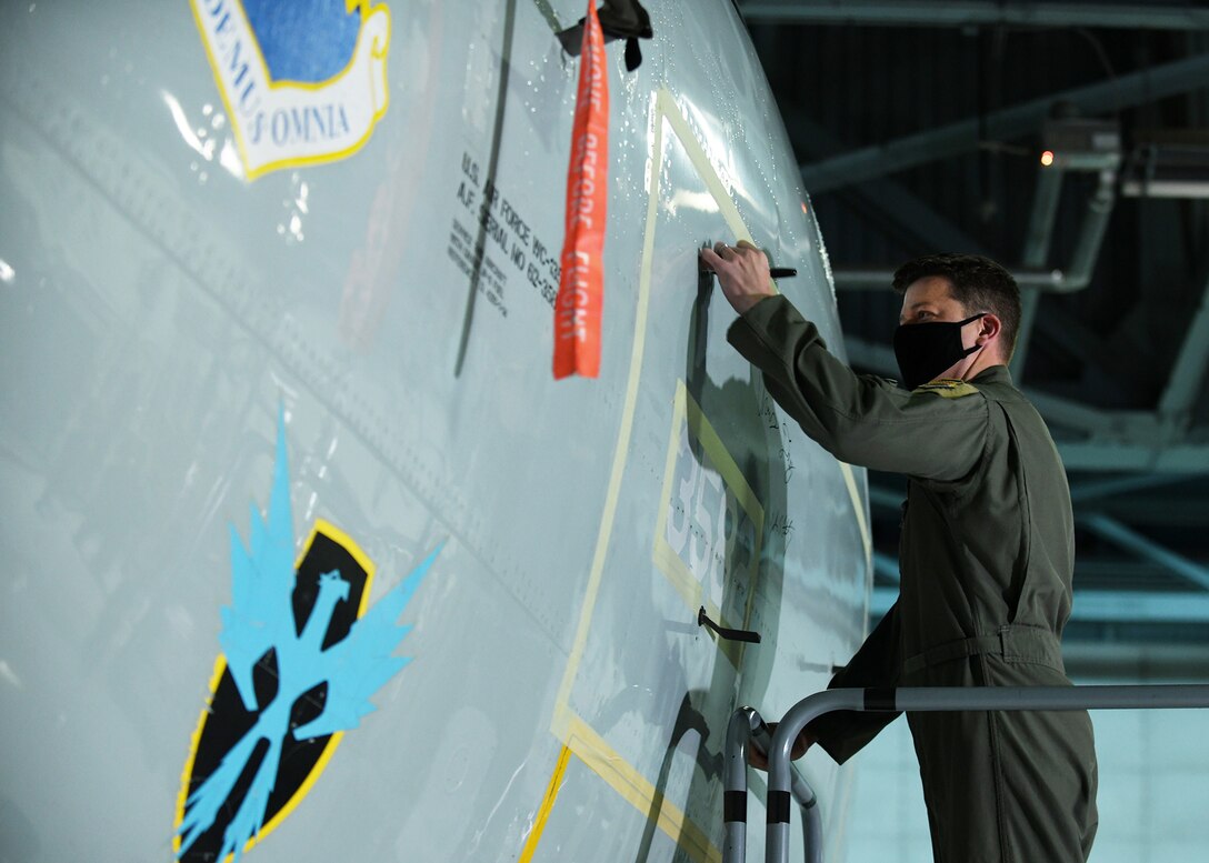 Man in flight suit signs aircraft as it is retired.