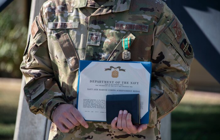 Staff Sgt. Thomas Waters holds his certificate after being awarded the Navy and Marine Corps Achievement Medal.