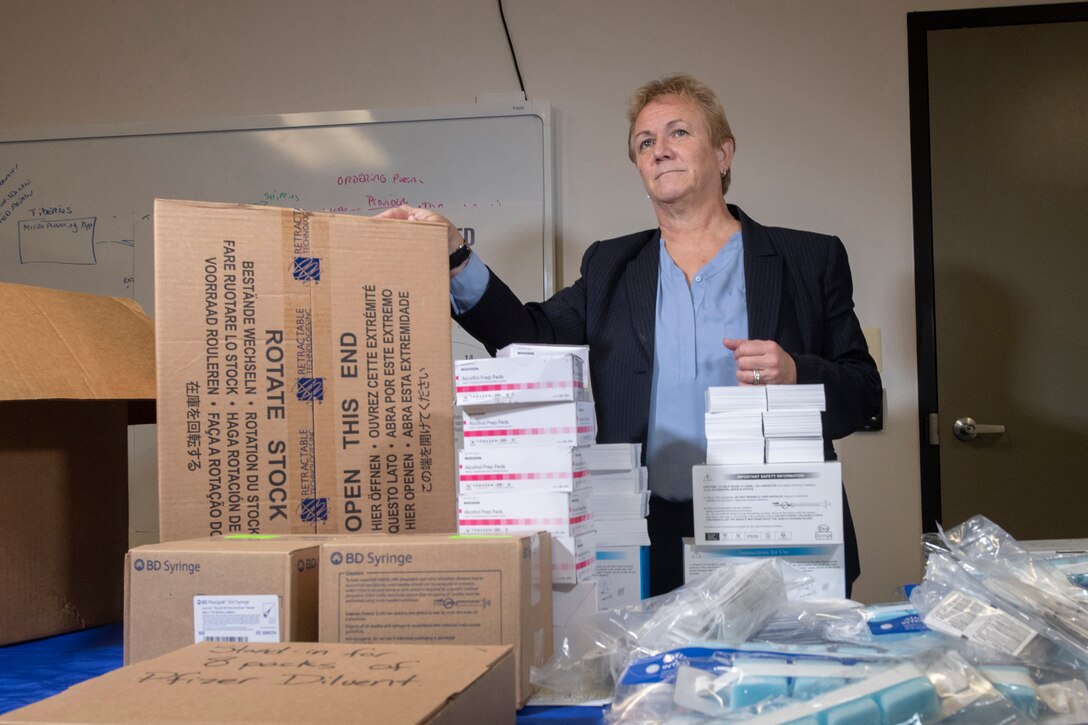 A woman stands behind a table filled with boxes.