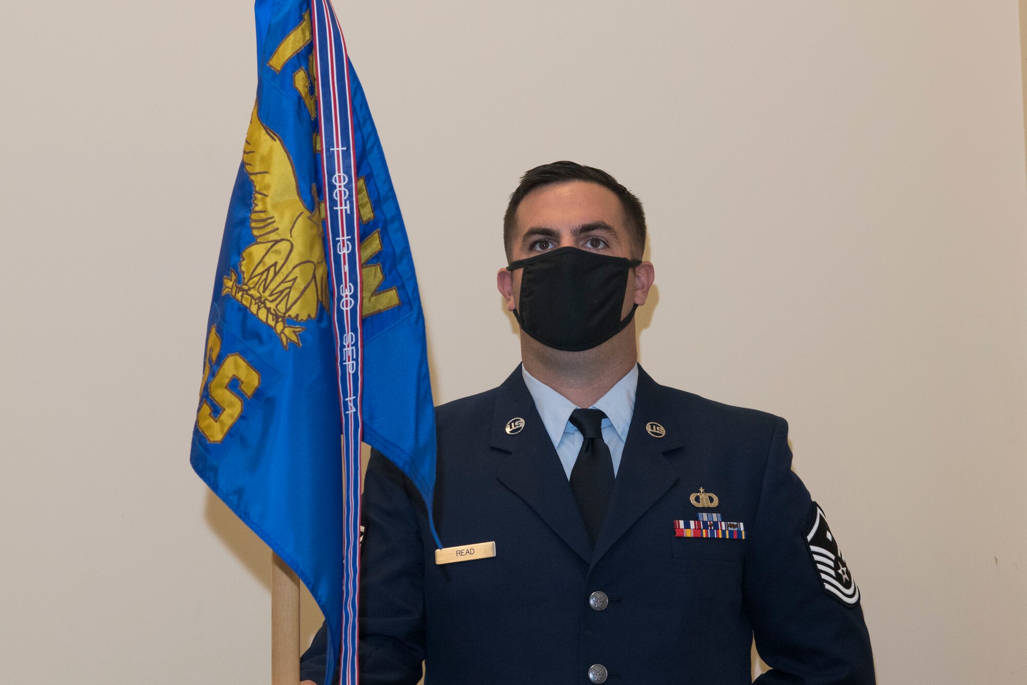 An Airman stand at attention while holding the unit's guidon