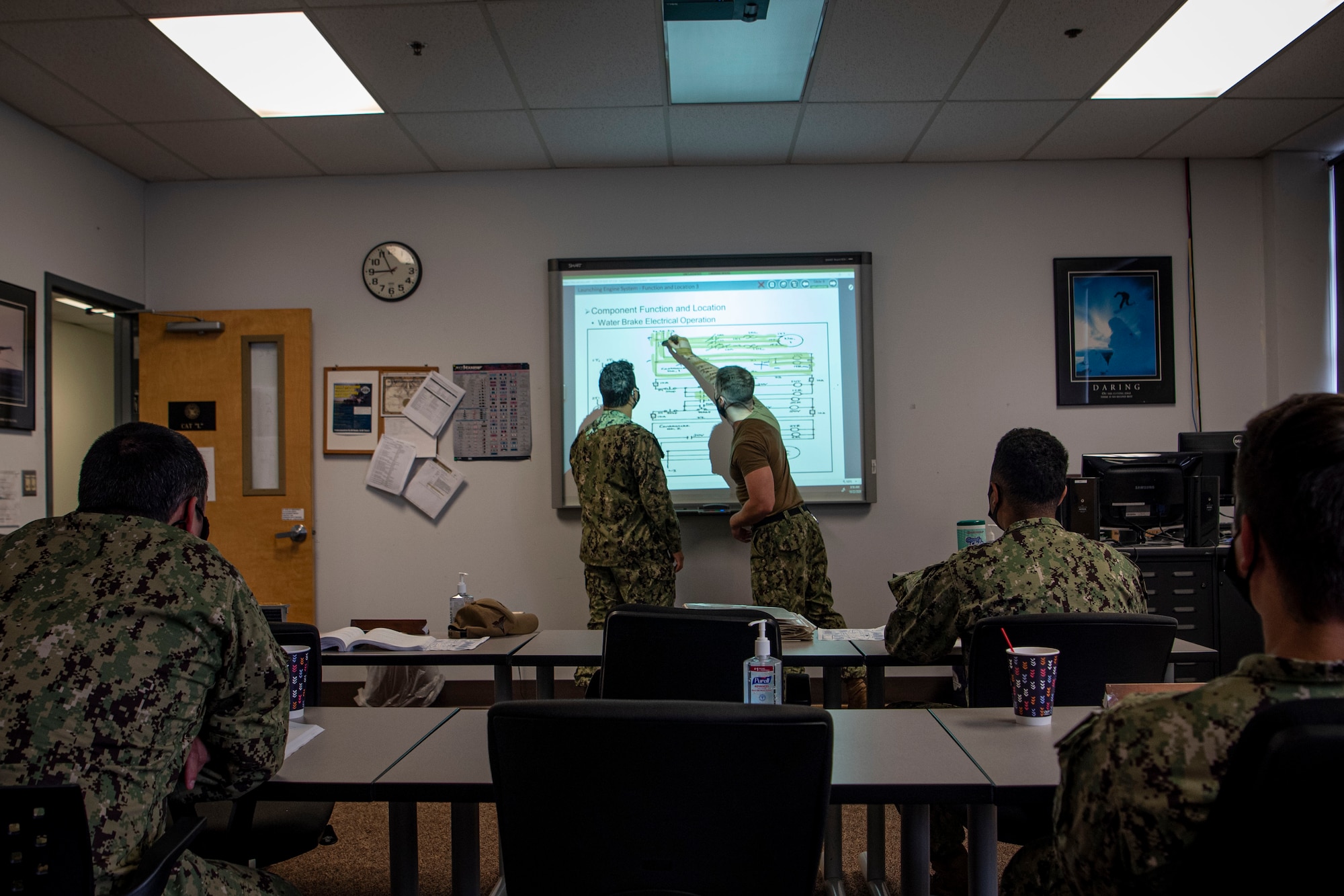 Photo of sailors writing on a whiteboard.
