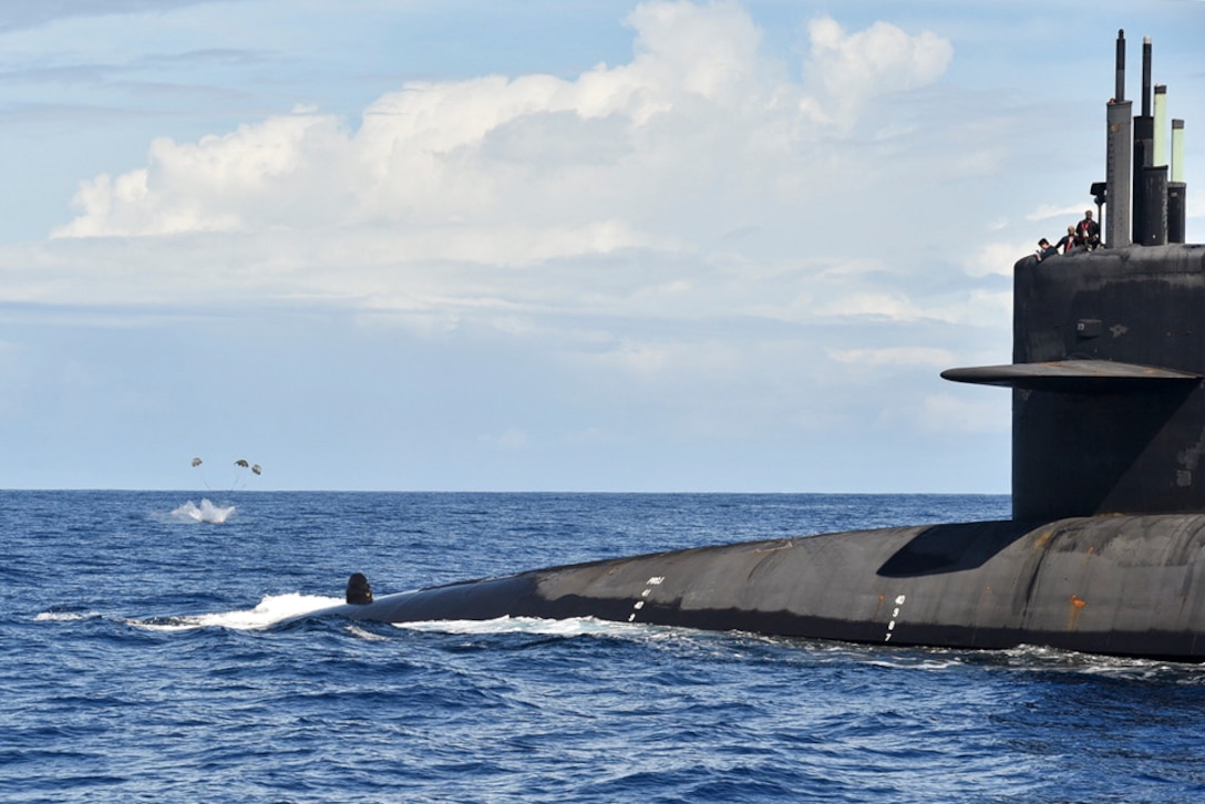 A package splashes in the water near a submarine.
