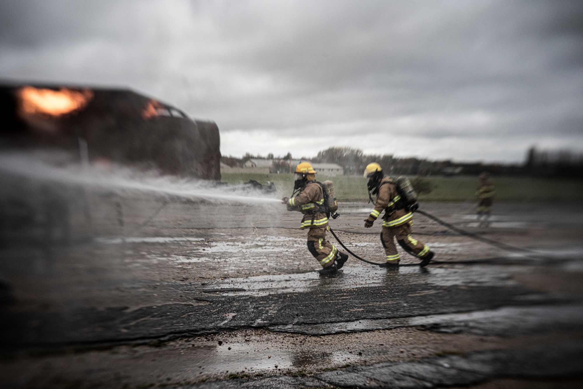 Robert Fisher, 422d Fire Emergency Services firefighter, left, and Christopher Hughes, 422d Fire Emergency Services firefighter, right, use a new Rosenbauer PANTHER vehicle to fight a fire at the mobile aircraft firefighting trainer at RAF Fairford, England, Oct. 23, 2020. The new vehicle more than doubles the amount of time that firefighters can fight an airfield fire before needing resupply. (U.S. Air Force photo by Tech. Sgt. Aaron Thomasson)