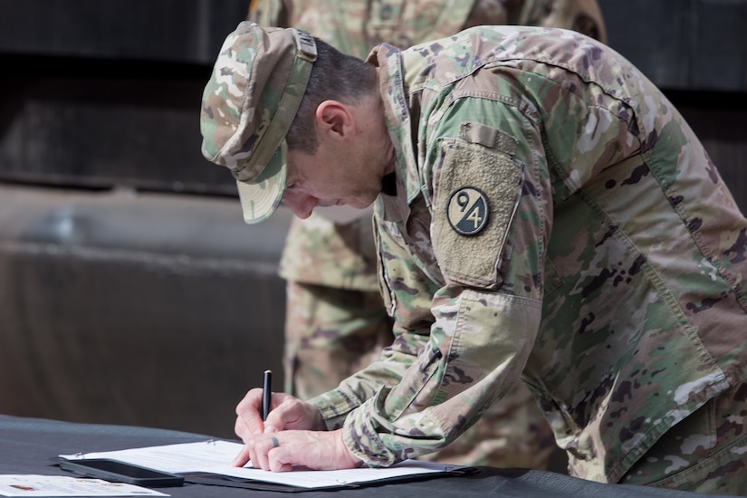 Soldier signing memorandum of agreement at ceremony