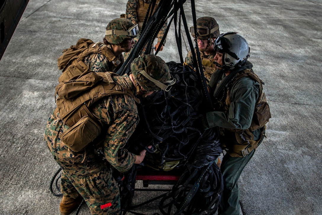 Marines handle cargo on a flightline.